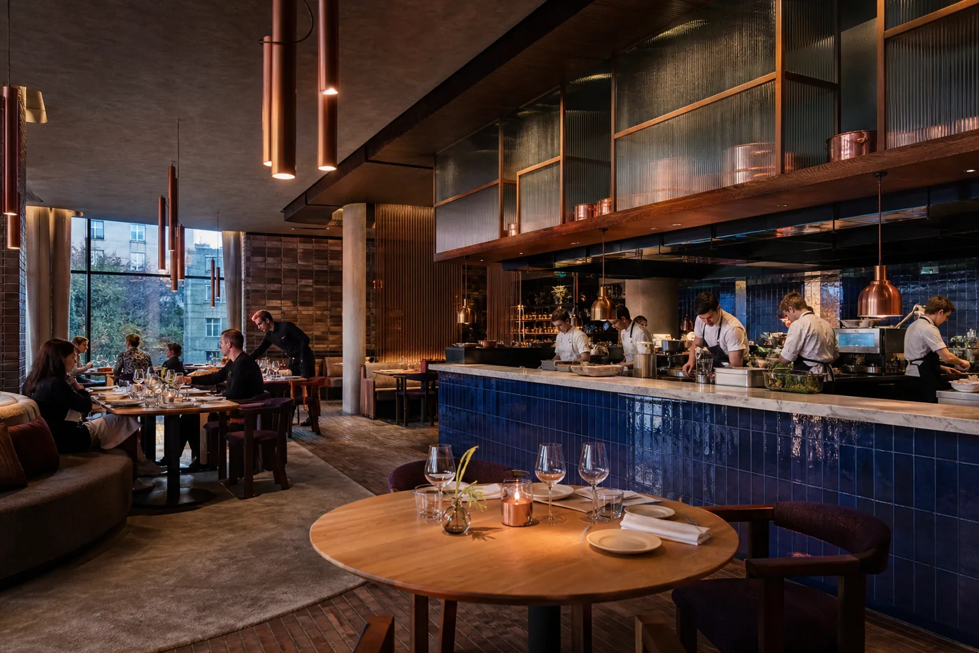 Restaurant met open keuken, blauwe tegels, eikenhout en warme avondverlichting